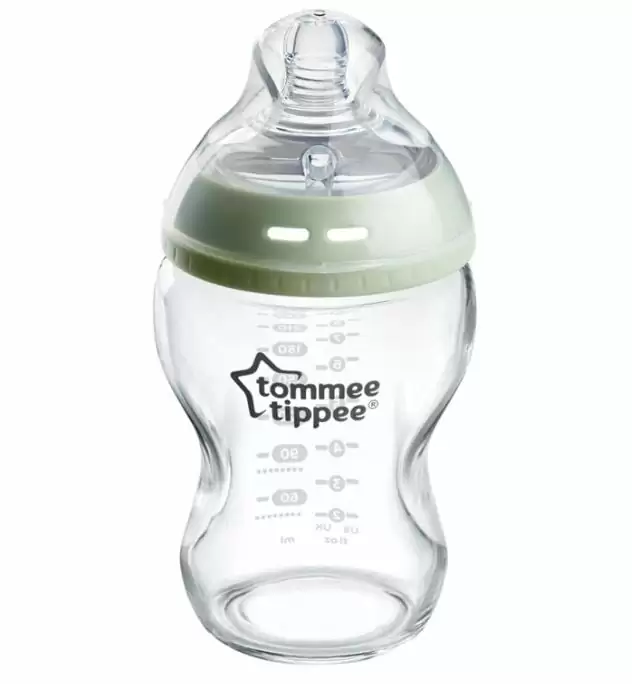 A glass bodied baby bottle with a green rim, by tommee tippee